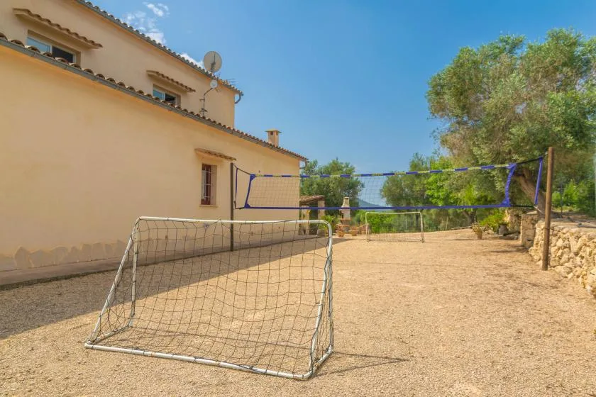 Un patio exterior de tierra junto a una casa, con una red tendida a través del espacio.