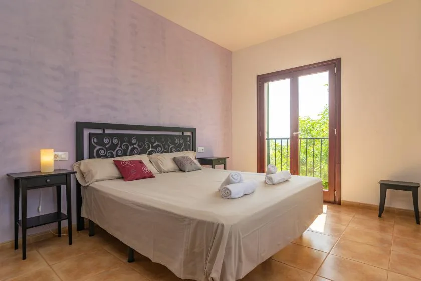 Un dormitorio con una cama grande y una puerta de cristal que da a un balcón.