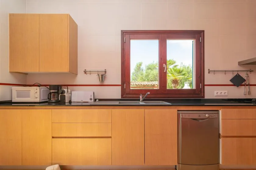 Una cocina con armarios de madera, una encimera y una ventana sobre el fregadero.