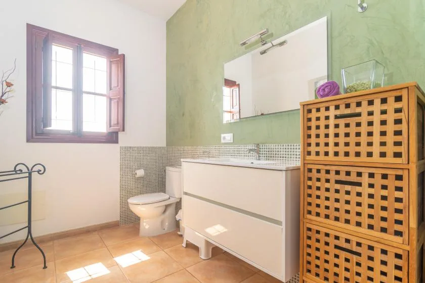 Un baño con lavabo, inodoro y una ventana.