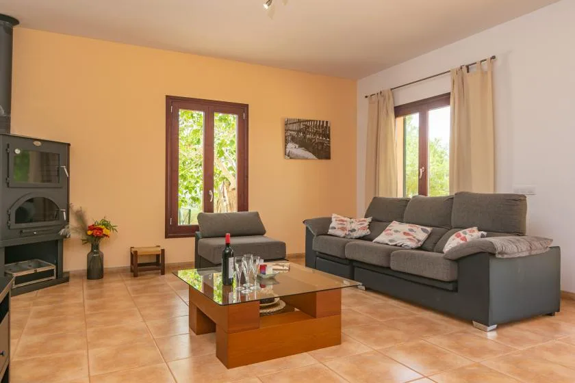Una sala de estar con asientos grises, una mesa de centro de cristal y dos ventanas.