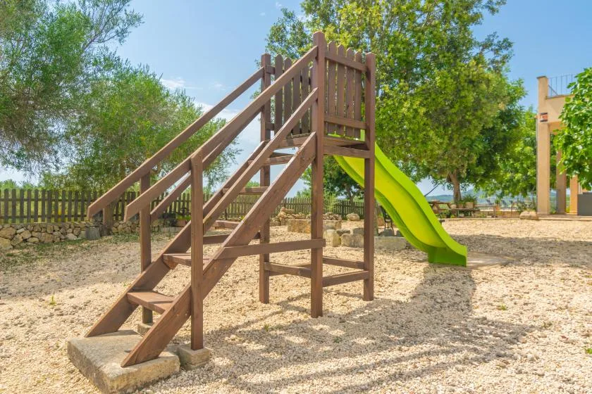 Un parque infantil al aire libre con una estructura de madera y un tobogán verde.