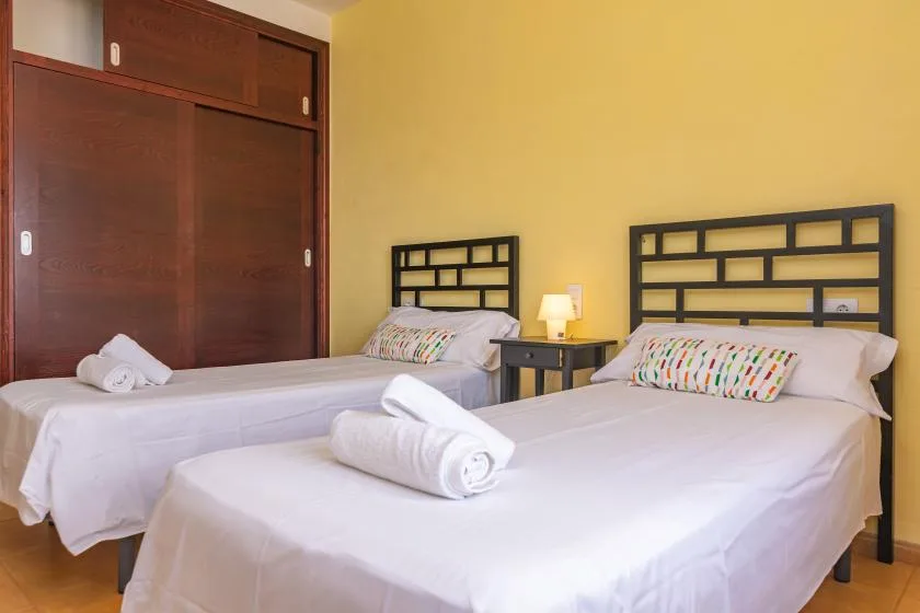 Un dormitorio con dos camas, ropa de cama blanca y cabeceros de madera oscura.