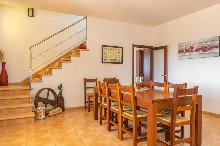 Un comedor con una mesa y sillas de madera junto a una escalera.