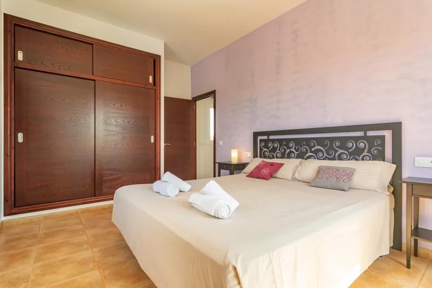 Un dormitorio con una cama grande, un cabecero estampado y un armario de madera oscura.