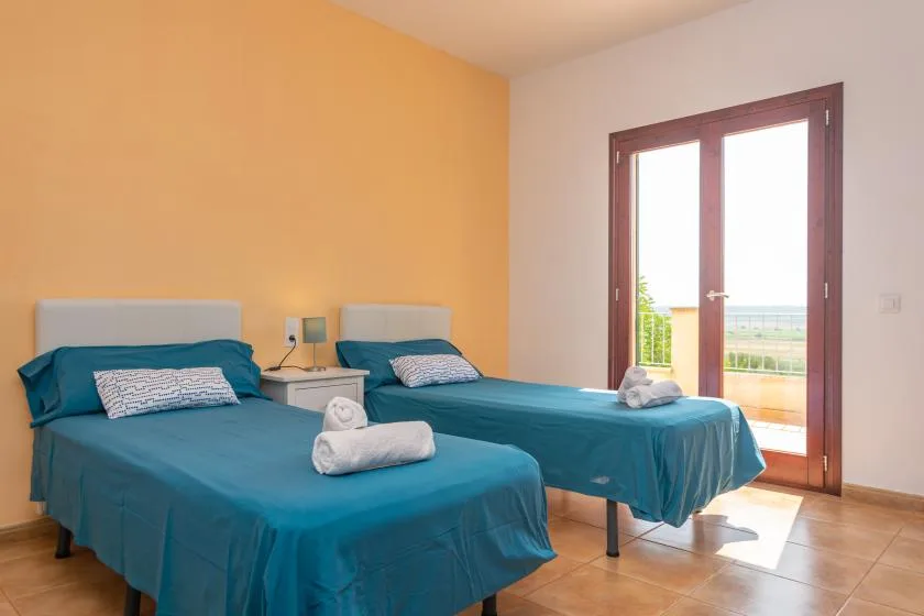 Un dormitorio con dos camas vestidas de azul junto a puertas de vidrio.