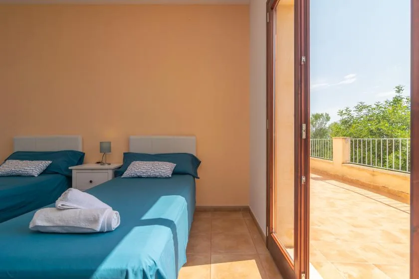 Un dormitorio con dos camas junto a una puerta de cristal abierta que da a una terraza.