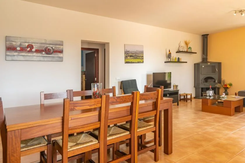 Comedor con una mesa de madera y sillas junto a una sala de estar.
