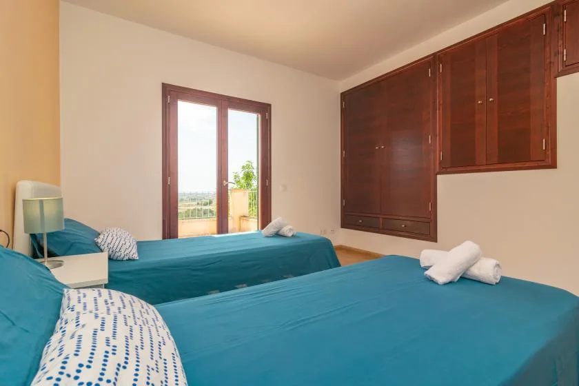 Un dormitorio con dos camas cubiertas con ropa de cama verde azulado y una ventana.
