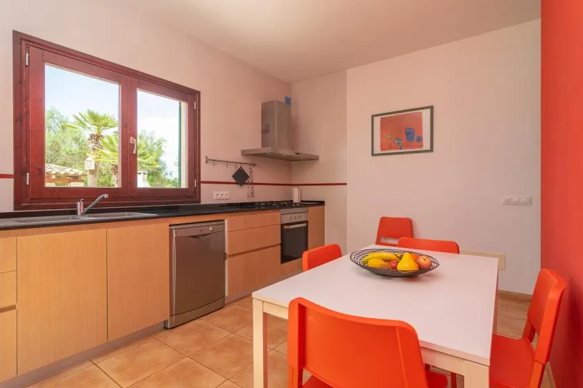 Una luminosa cocina y comedor con armarios de madera y una mesa blanca.