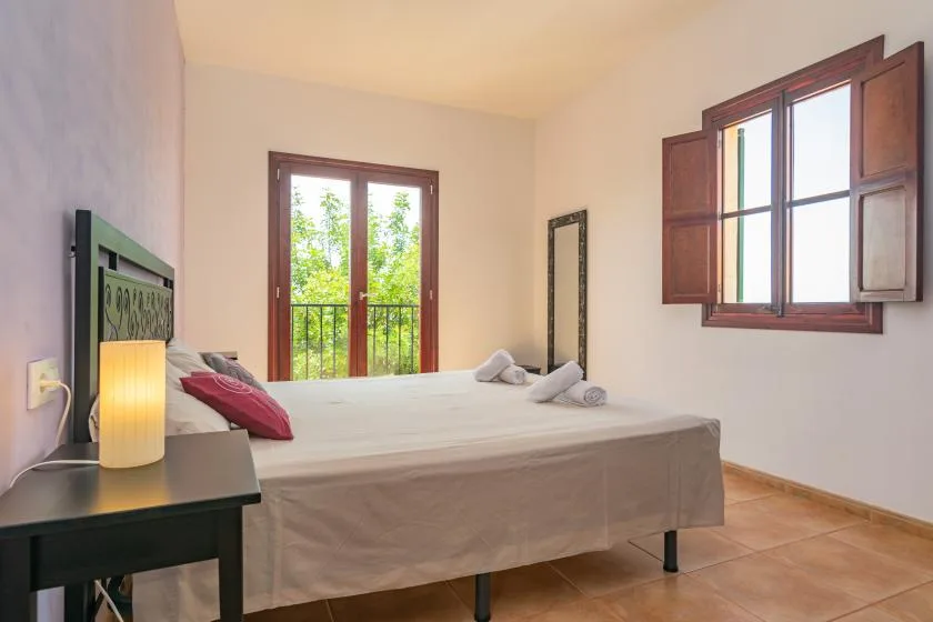 Un dormitorio con una cama junto a una ventana con vista a la vegetación.