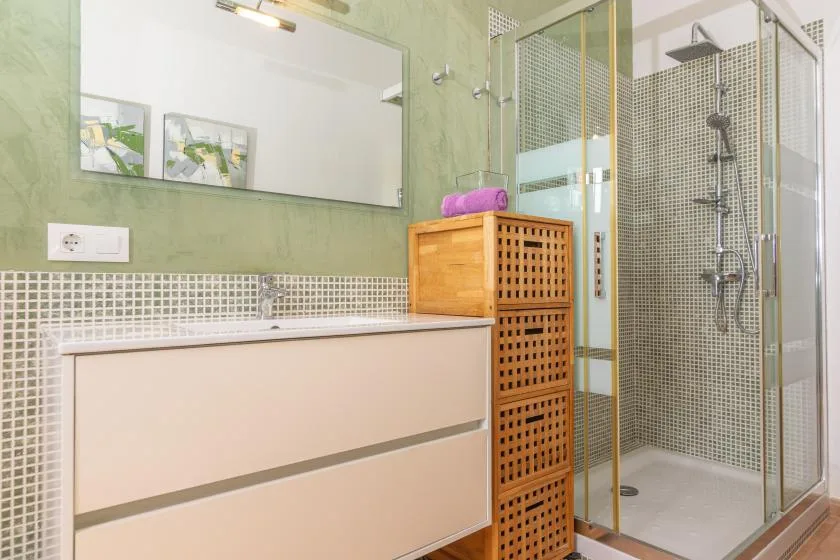 Un baño con un lavabo y una ducha con mampara de vidrio.