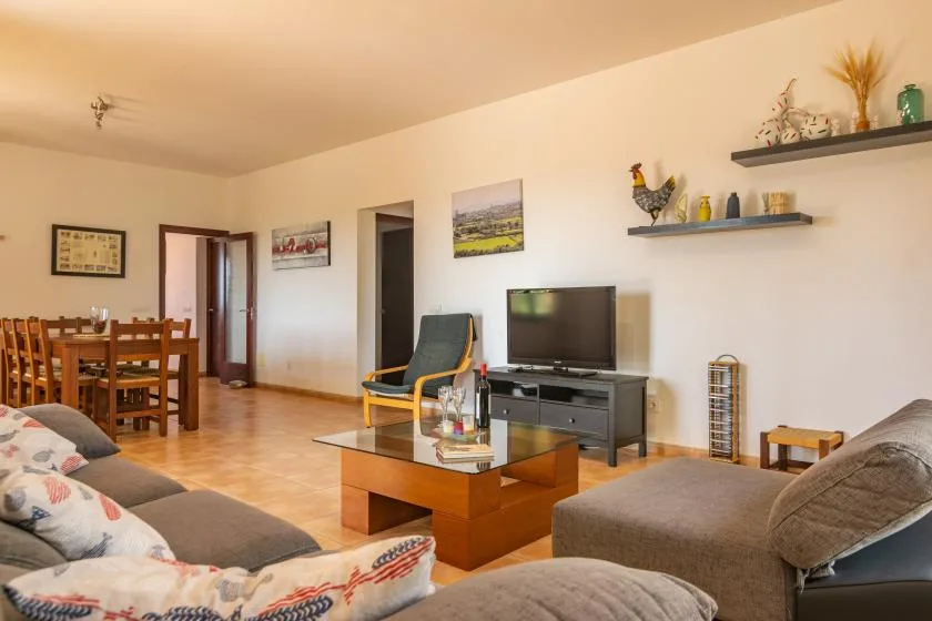 Una sala de estar con televisor, asientos y una mesa de comedor de madera.