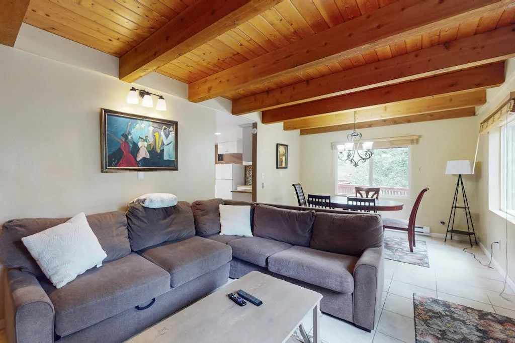 Living room with sectional seating beneath a wooden-beam ceiling.