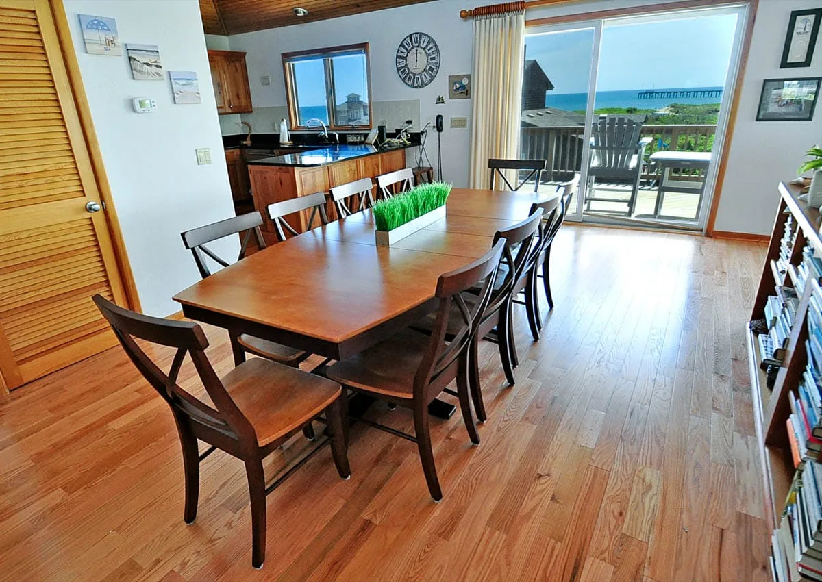 Comedor con una mesa larga de madera y puertas corredizas de vidrio hacia un balcón.