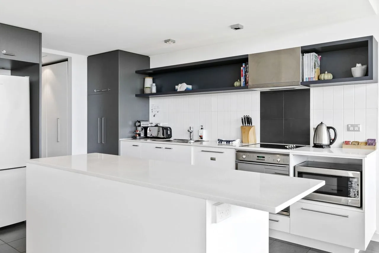 Una cocina moderna con armarios blancos y una isla grande.