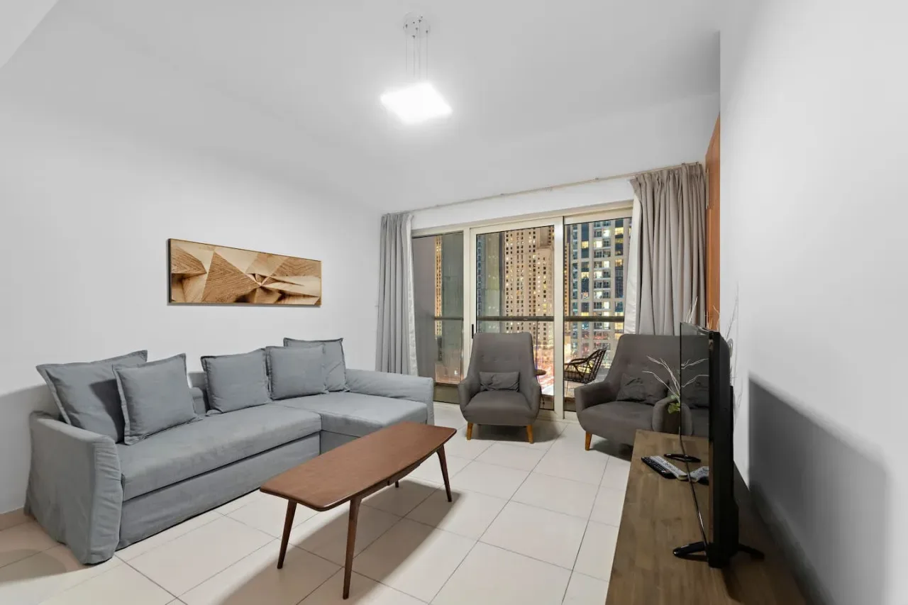 A bright living room with seating, a coffee table, and large windows.
