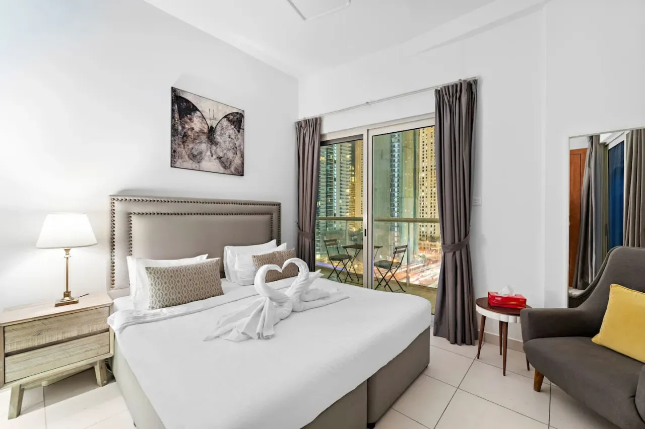 Un dormitorio luminoso con una cama bien hecha y grandes puertas de vidrio.