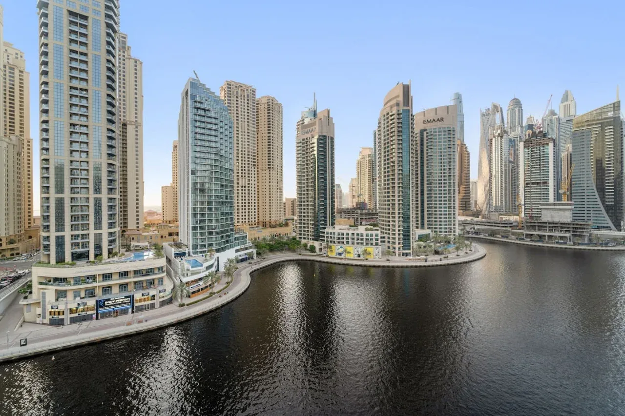 A waterfront cityscape shows tall buildings lining a curved canal.