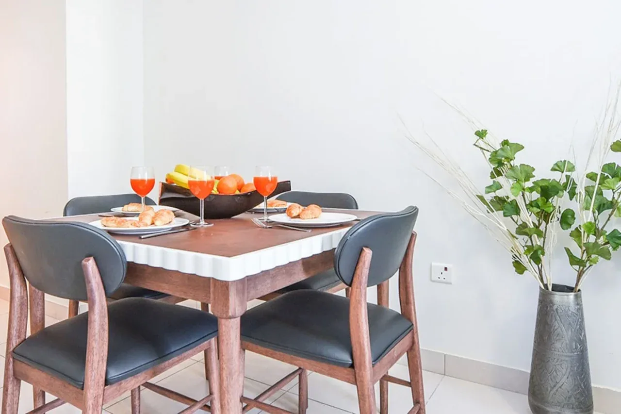 A dining table is set with food and drinks beside a leafy plant.