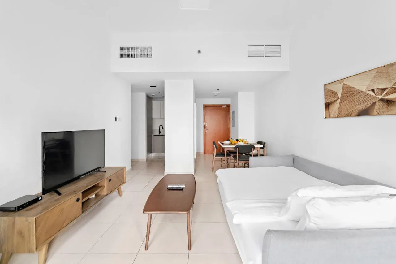 A bright living area with a television, coffee table, and dining space.
