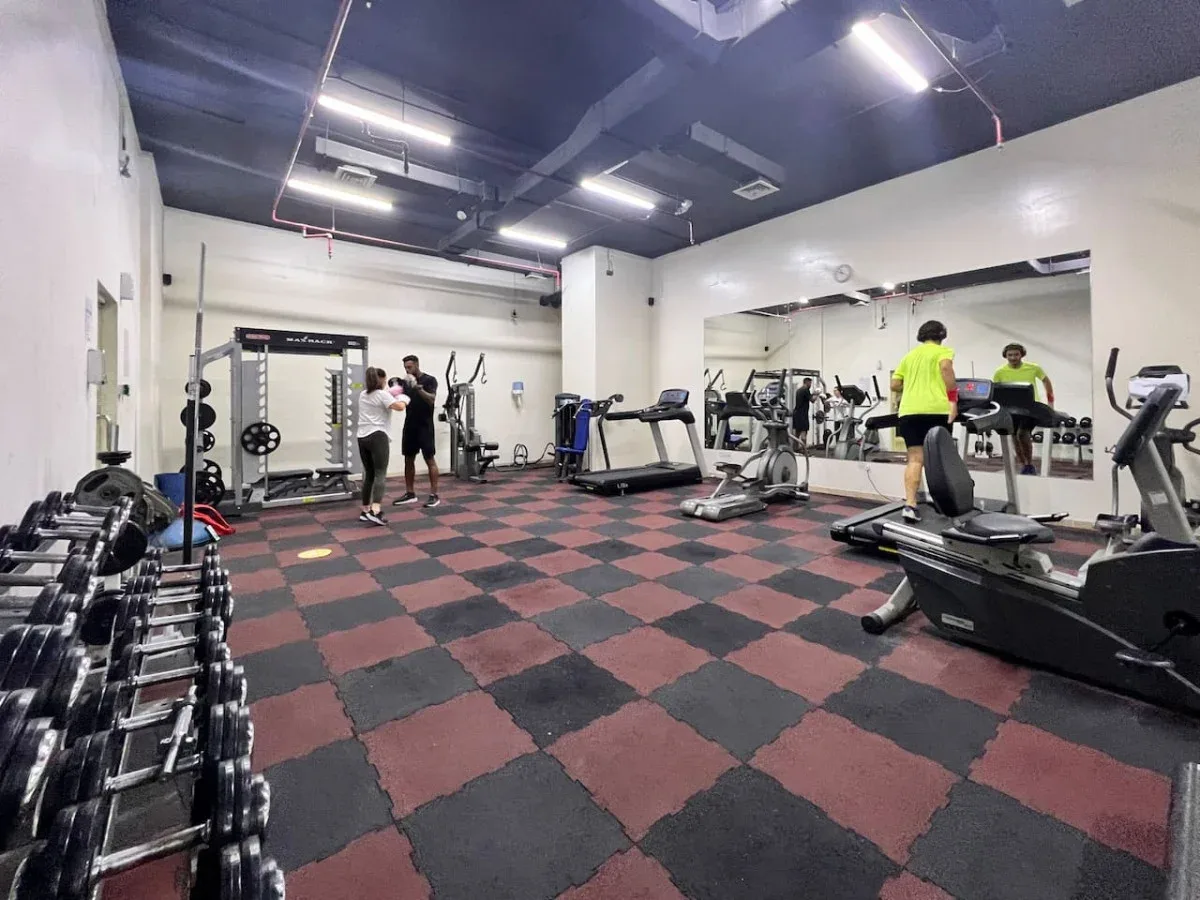 A gym with exercise machines, free weights, and a mirrored wall.