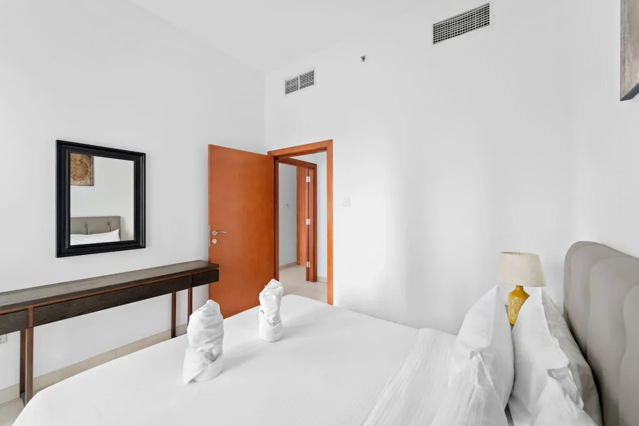 A bedroom with a neatly made bed and an open doorway.