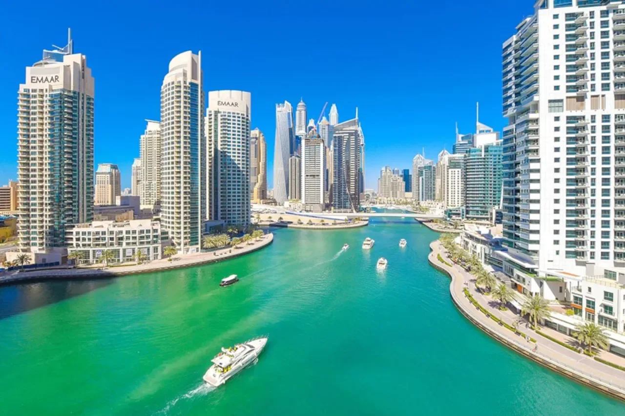 A city waterfront with high-rise buildings lining a turquoise canal.