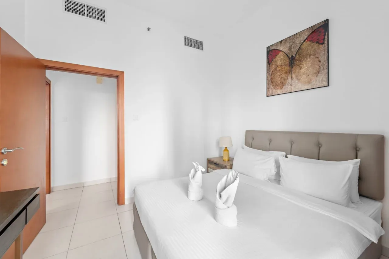 A bedroom with a neatly made bed and abstract wall art.