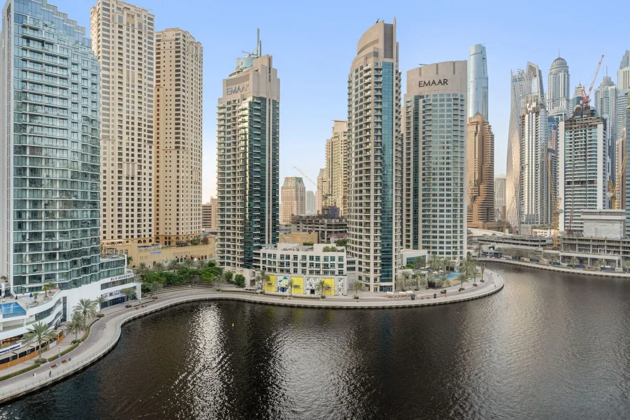 A cluster of high-rise buildings stands beside a curving waterfront.