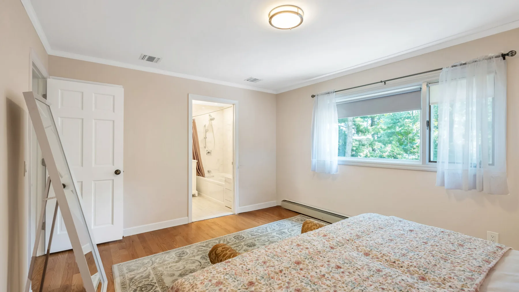 Un dormitorio con una colcha estampada, una ventana y una puerta abierta.