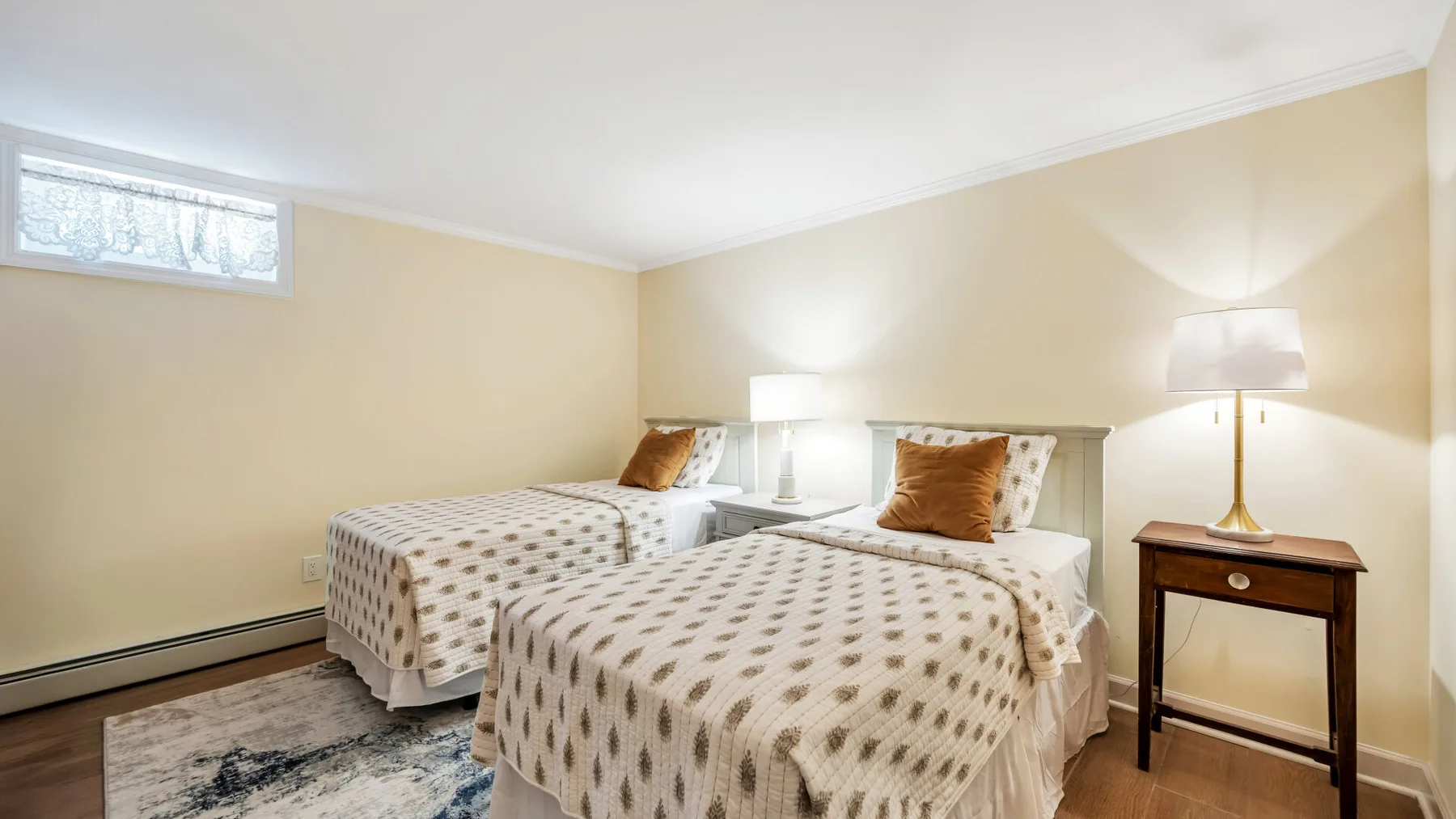 Un dormitorio con dos camas, mesitas de noche y una alfombra estampada.