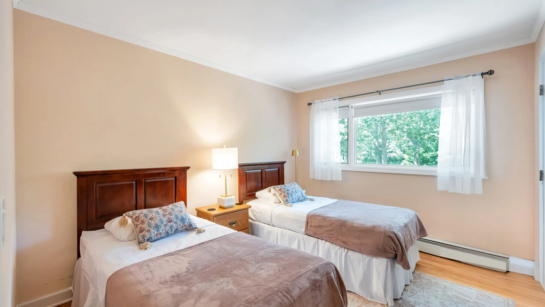 Un dormitorio con dos camas y una ventana amplia con vista a los árboles.