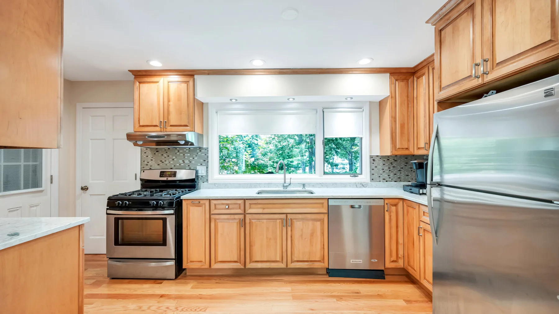 Una cocina luminosa con gabinetes de madera, una ventana y electrodomésticos de acero inoxidable.