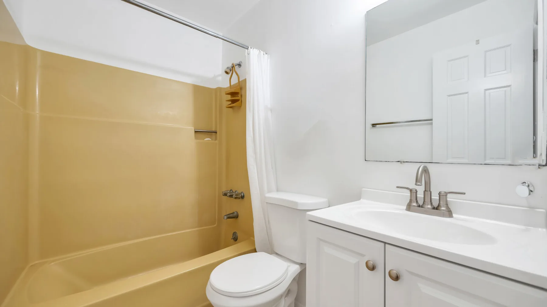 Un baño con bañera, inodoro y lavabo bajo un espejo grande.