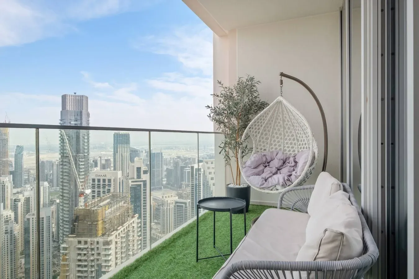 Un área de estar en un balcón con una silla colgante y vistas al horizonte urbano.