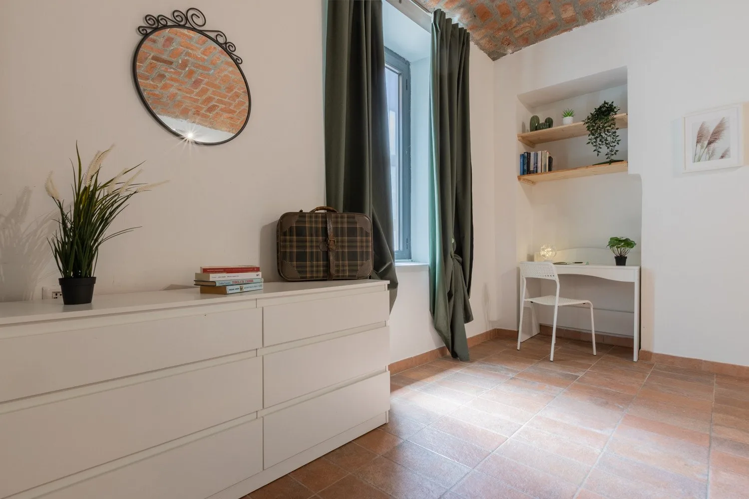 A bright room features a desk, shelves, and a large white dresser.