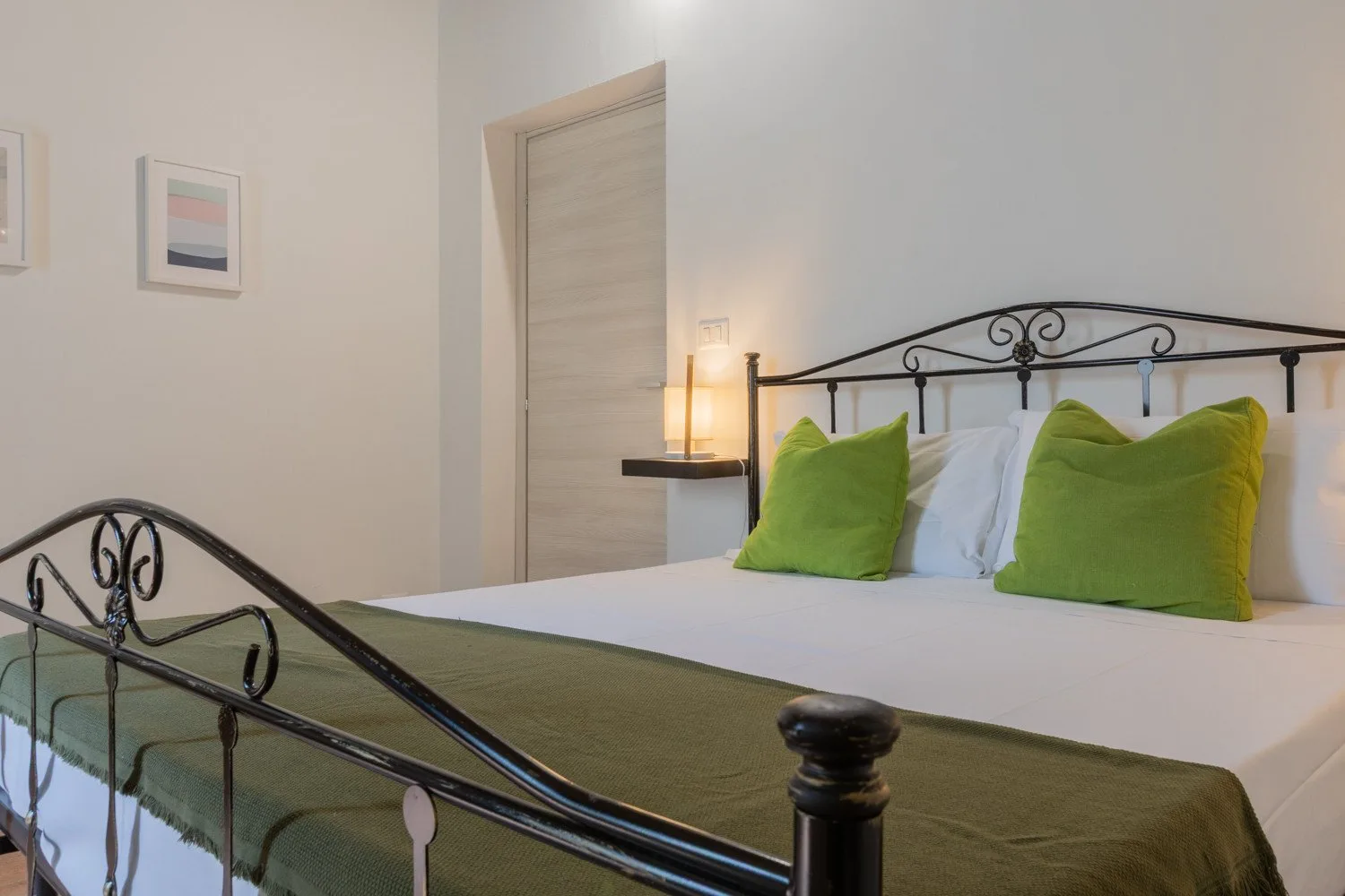 Bedroom with a bed dressed in white and green bedding.