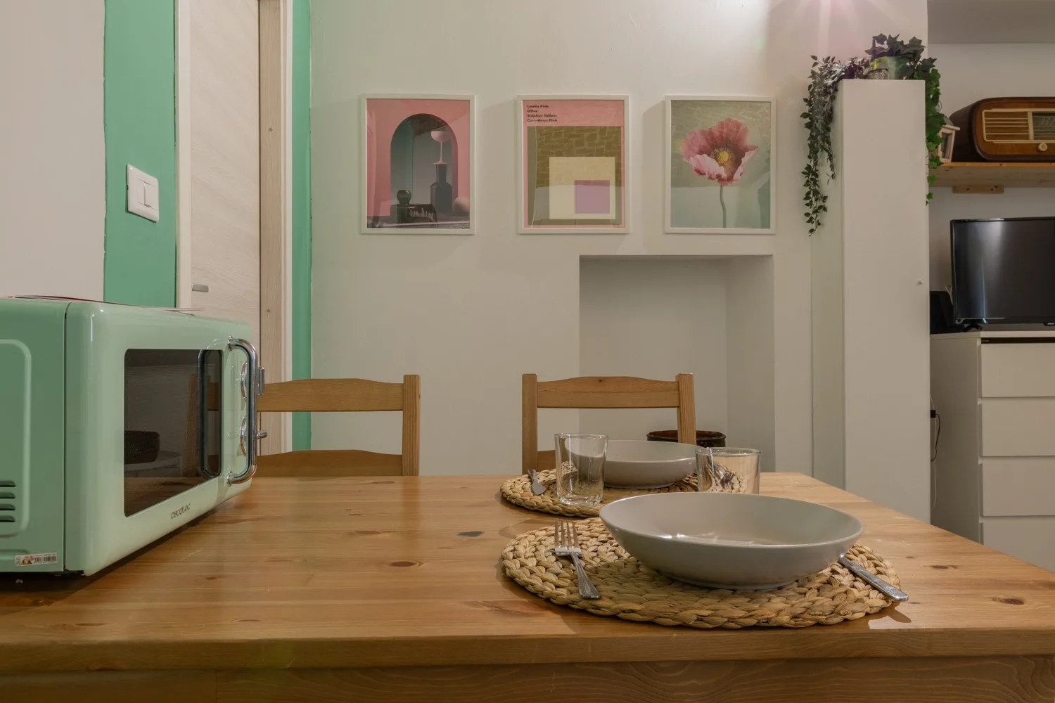 A dining area with a wooden table, chairs, and framed artwork on the wall.