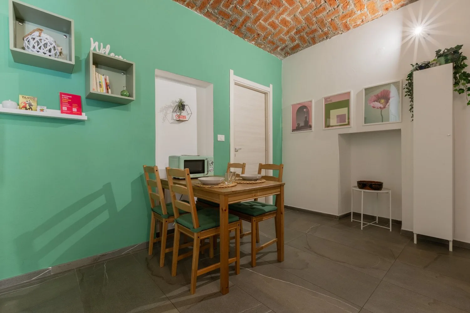 A dining area with a wooden table and chairs beside a green wall.