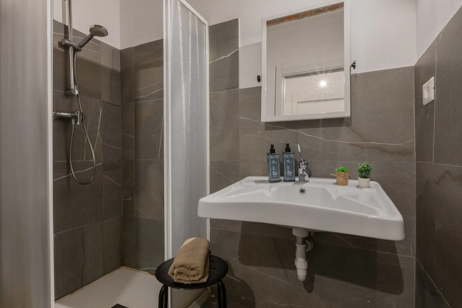 A tiled bathroom with a shower, wall mirror, and sink.