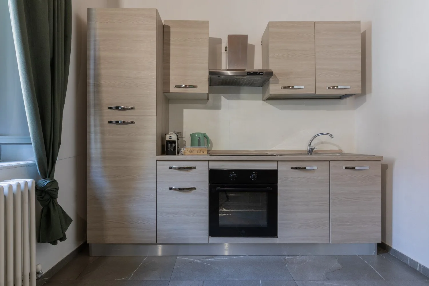 A compact kitchen with light wood cabinets, a countertop, and an oven.