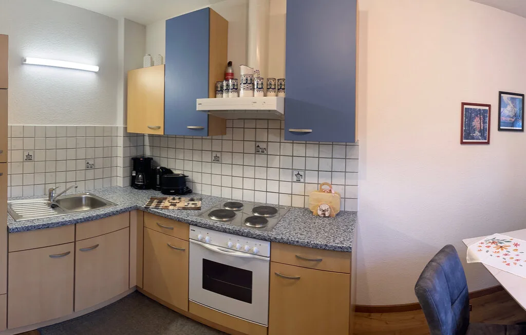 Una cocina compacta con fregadero, cocina y horno junto a una pequeña zona de comedor.