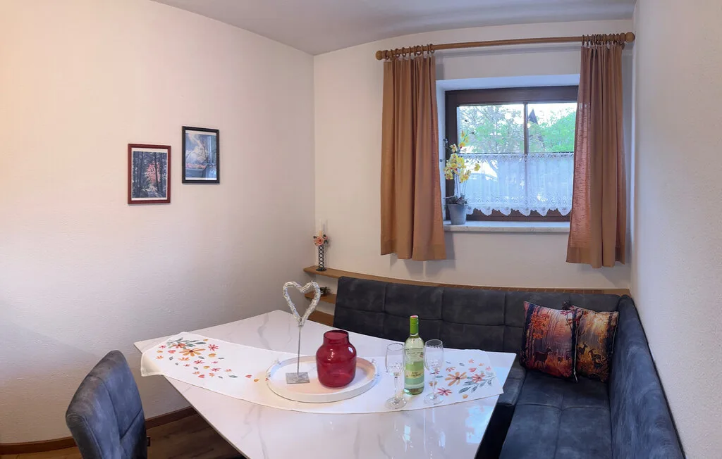 Un rincón de comedor con mesa y asientos junto a una ventana con cortinas.