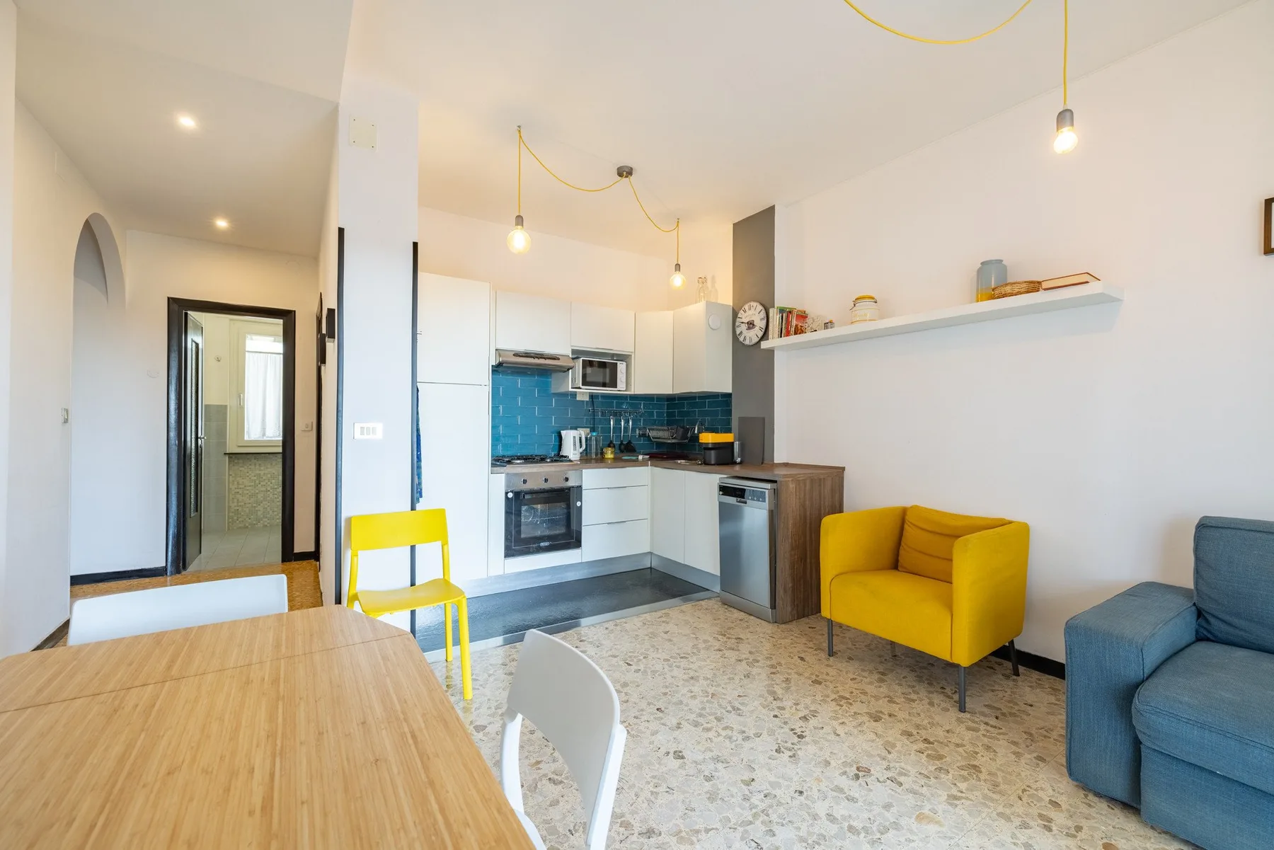 Una luminosa cocina con comedor, un sillón amarillo y un salpicadero de azulejos azules.