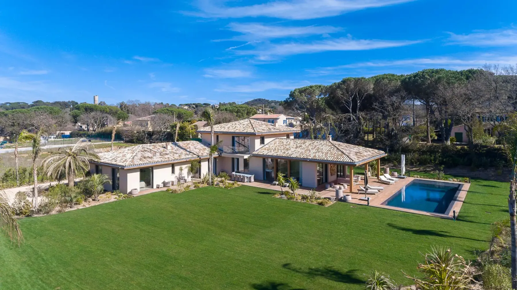 Un jardín cuidado rodea una casa grande con piscina.