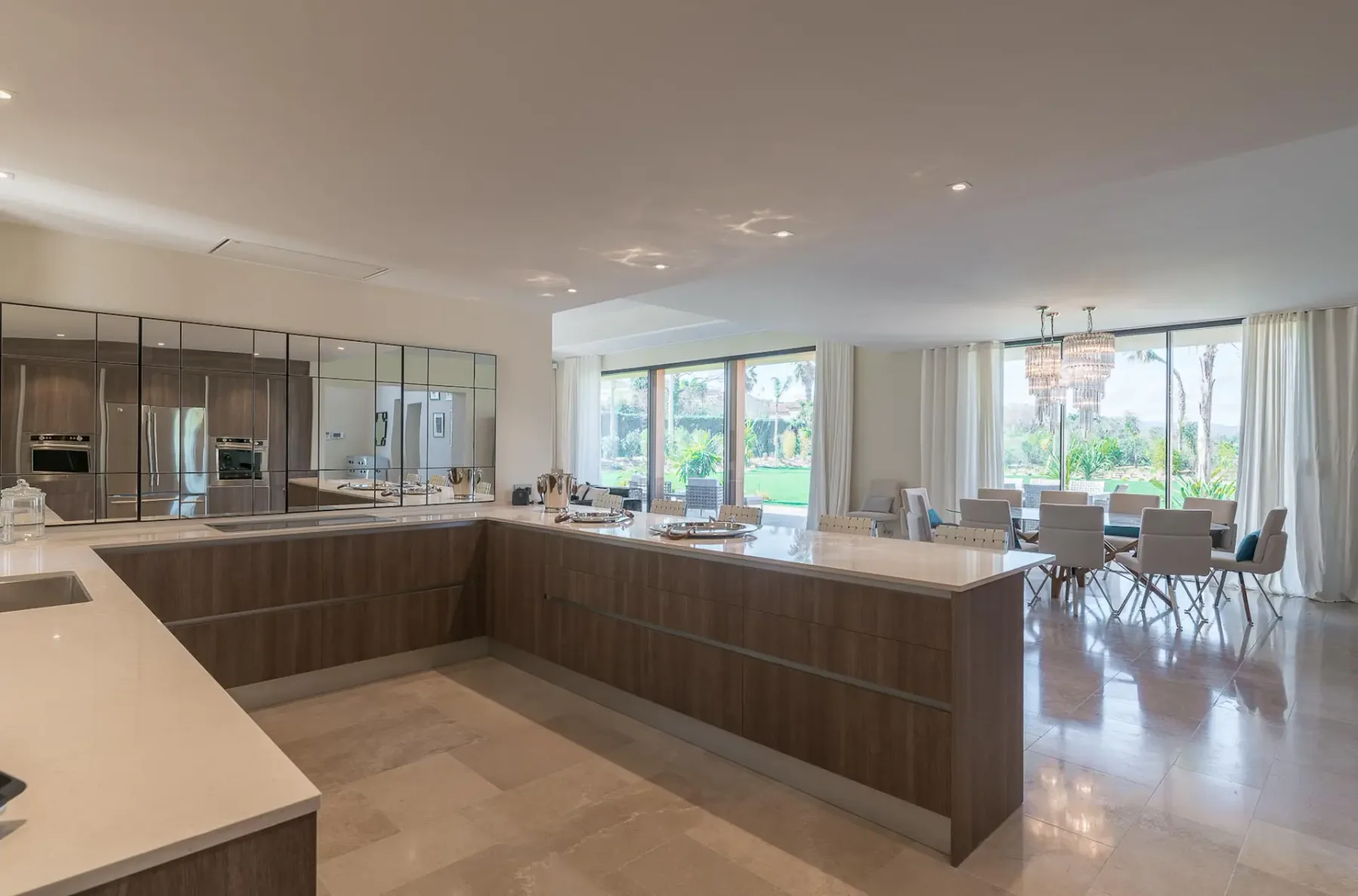 Amplia cocina moderna con isla alargada con asientos de barra y una mesa de comedor al fondo