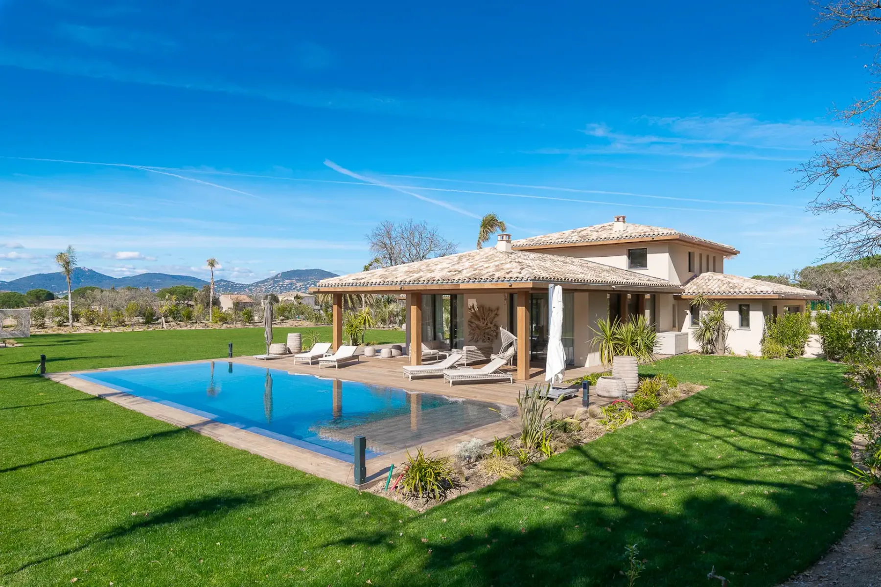 Vista desde el patio trasero del jardín con césped, la piscina y la terraza