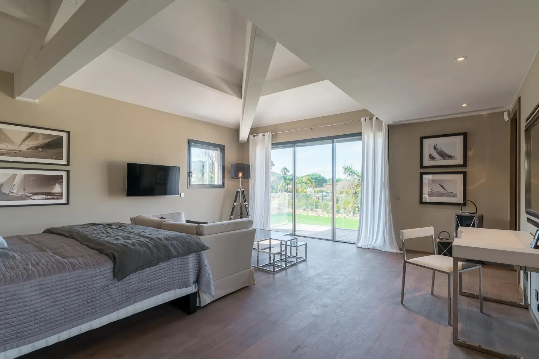 Dormitorio grande con cama y un pequeño sofá frente a una gran puerta corredera de cristal que da al exterior