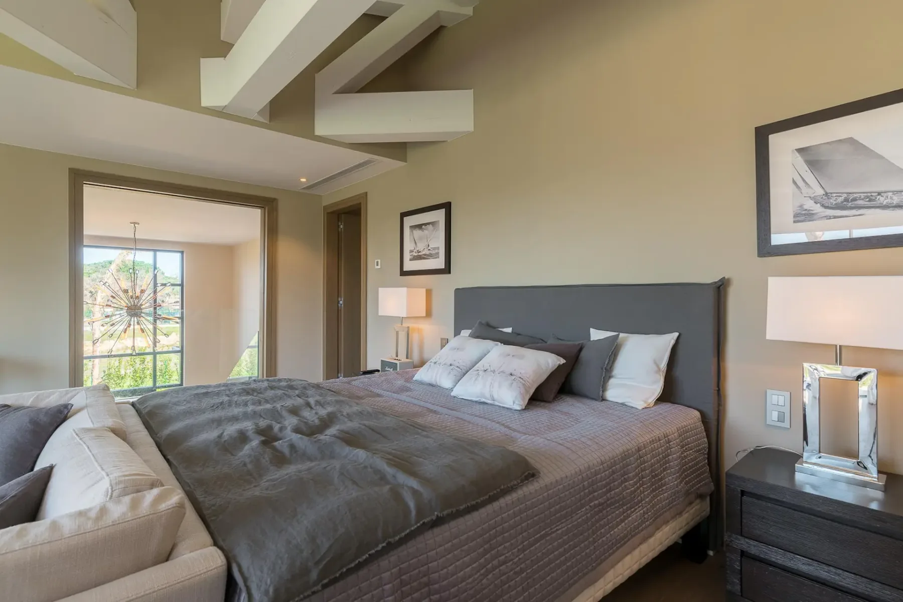 Un dormitorio con una cama junto a una puerta abierta a una habitación luminosa.